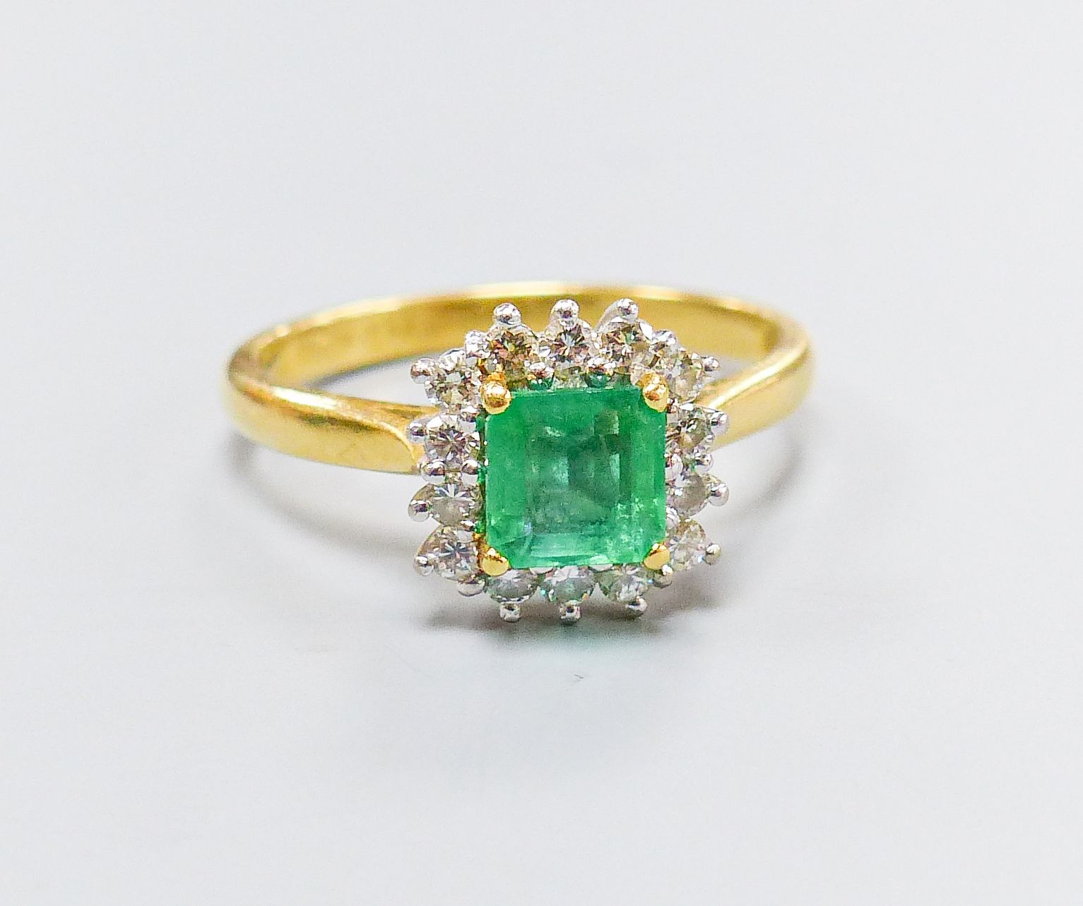 A modern 18ct gold, emerald and diamond set square cluster ring, size O, gross weight 4.3 grams.
